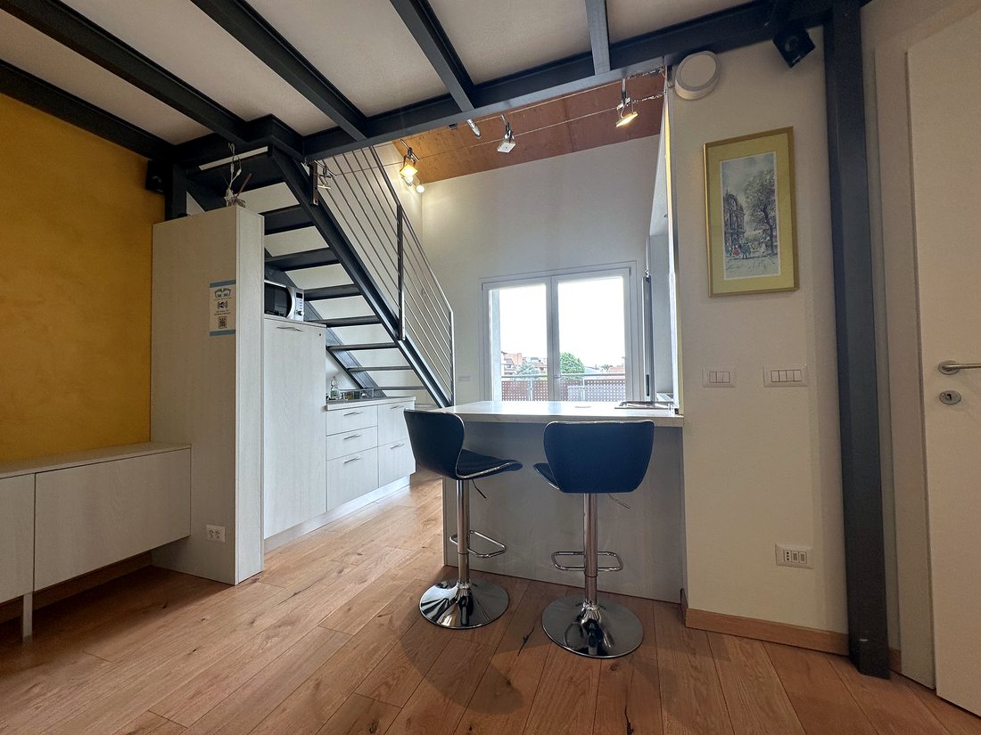 Vista d'insieme del loft con scala, finestra e piano snack
