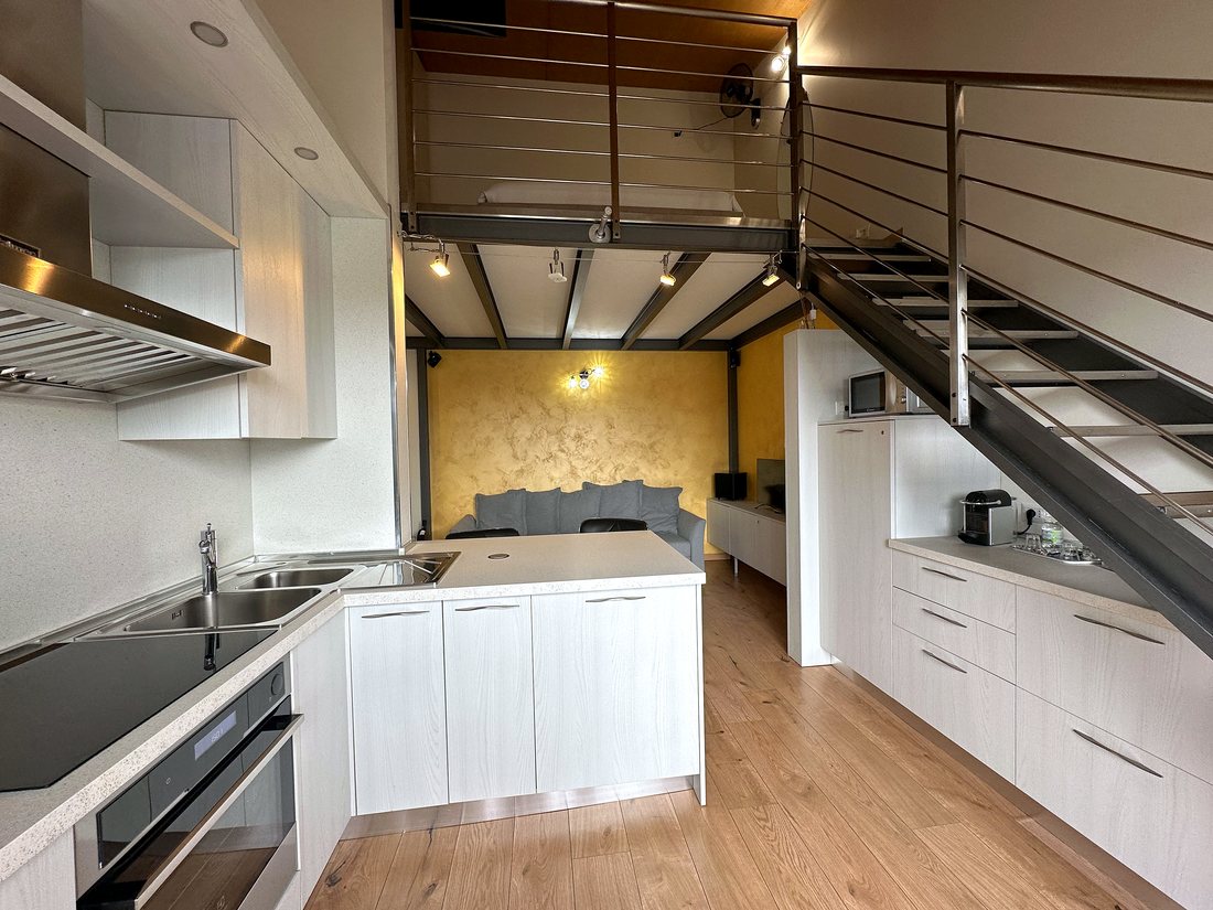Cucina bianca del loft con forno, lavastoviglie e piano cottura
