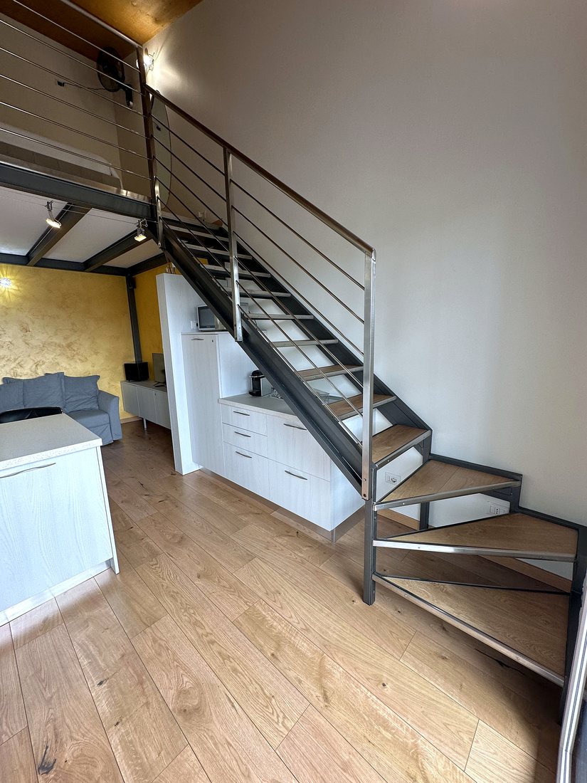 Scala in acciaio e vetro che collega i due livelli del loft