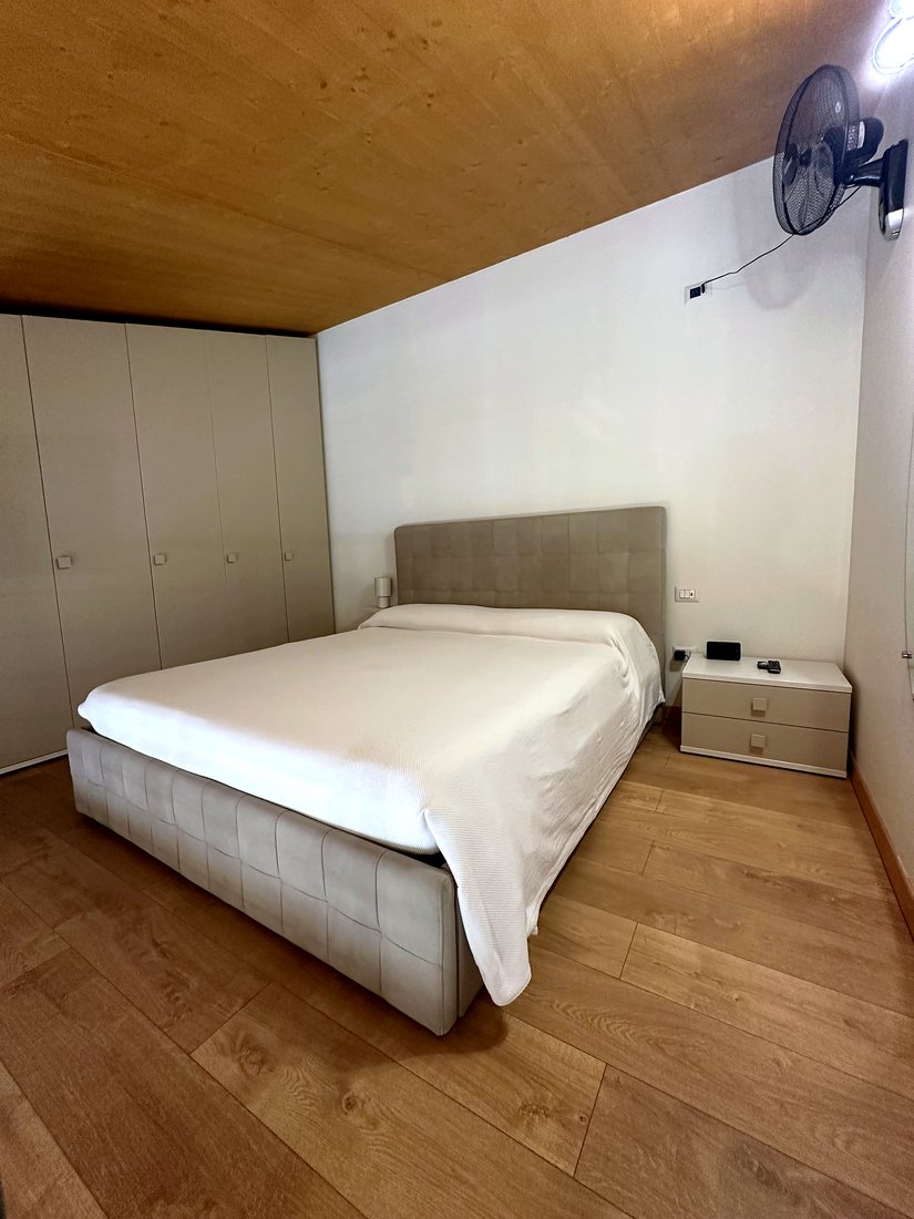 Letto matrimoniale con comodini e ventilatore a parete
