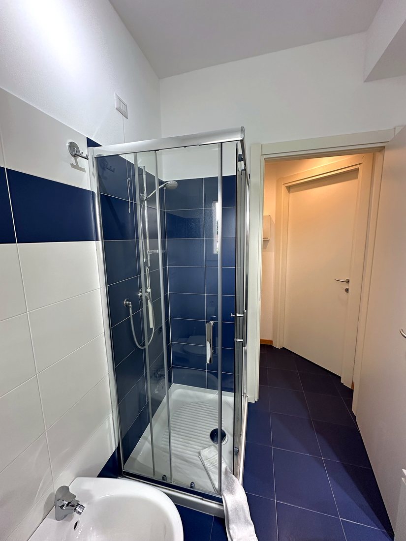 Bagno del loft con box doccia in vetro e piastrelle blu