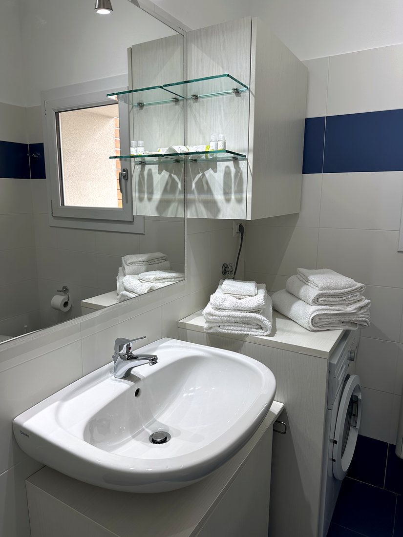 Lavabo del bagno con asciugamani puliti e lavatrice